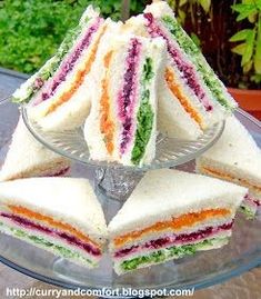 there are several sandwiches stacked on top of each other in a glass platter with one cut in half