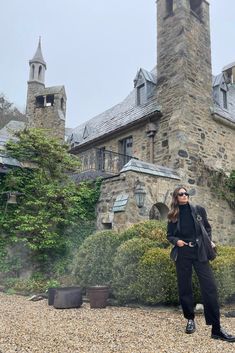 a woman standing in front of a stone building