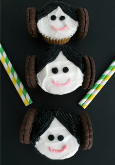 three cupcakes with white frosting and black hair