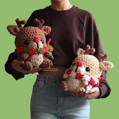 a woman is holding two small crocheted reindeers with flowers on their heads