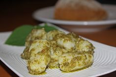 some food is sitting on a white plate with green leaves and bread in the background