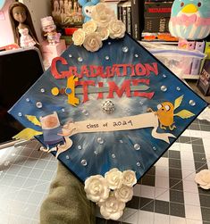 a decorated graduation cap sitting on top of a table in front of books and toys