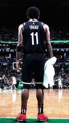 a man standing on top of a basketball court wearing black and red shoes with the number 11 on it