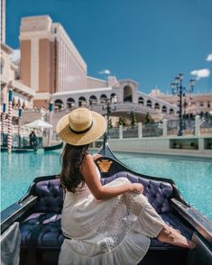 a woman in a straw hat is sitting on a gondola by the pool