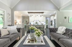 a living room with two couches and a coffee table in front of a kitchen