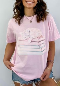 "This is a unisex sized comfort colors t-shirt with a cute coquette cat design with a bookish vibe. It is a high quality and durable material - famous for it's \"worn-in\" look and vintage inspired muted color options. This coquette aesthetic t shirt is a great gift/perfect for the cat lovers your life.  SIZE UP 1-2 SIZES FOR A TRENDY, LOOSE FIT!  *Product Description * - 100% ring spun cotton - Soft washed garment dyed fabric - Double needle collar - Twill taped neck and shoulders - Double need Bookish Short Sleeve T-shirt For Spring, Spring Bookish Short Sleeve T-shirt, Spring Bookish Style Short Sleeve T-shirt, Pink Crew Neck T-shirt With Bookish Style, Coquette Cat, Clothing Coquette, Coquette Clothing, Coquette Top, Coquette Shirt