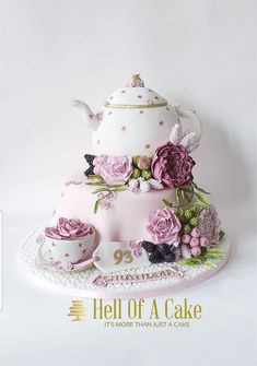 there is a cake with pink flowers on it and a teapot in the middle