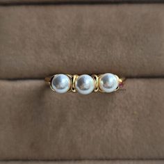 three pearl rings sitting on top of a brown cloth