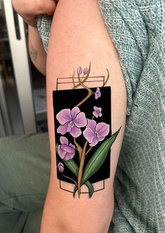 a woman with a tattoo on her arm has a purple flower and green leaves in it