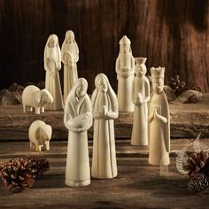 a nativity scene with figurines and pine cones on a wooden table in the background