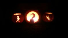 three carved pumpkins in the shape of people and an arrow on them, with one glowing