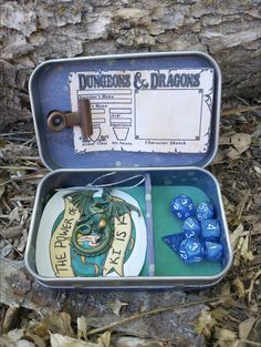 two tins with dice in them sitting on the ground next to a tree trunk