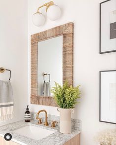 a bathroom with a sink, mirror and pictures on the wall above it is shown