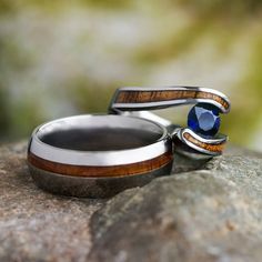 two wedding rings with wood inlays sit on top of a rock