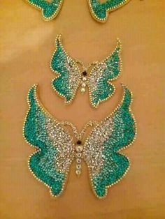 three pieces of jewelry with green and white wings