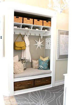 a white coat rack filled with lots of pillows and other items next to a chandelier