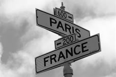 two street signs on top of each other in front of a blue sky with clouds