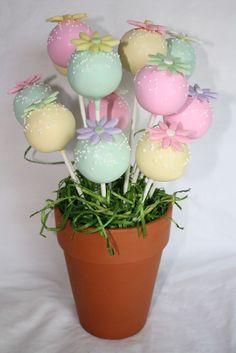 a potted plant filled with cake pops covered in pastel frosting and bowknots