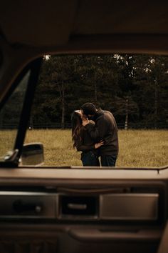 a man and woman kissing in the back of a car with trees in the background