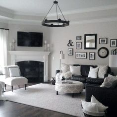 a black and white living room with pictures on the wall, couches, chair, coffee table and fireplace