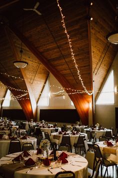 tables and chairs are set up in the middle of a large room with lights strung from the ceiling