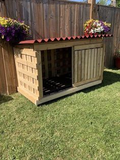 a dog house made out of pallets with flowers on top