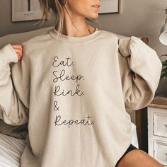 a woman wearing a sweatshirt that says eat sleep, drink and repeat