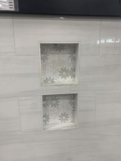 two square window in the middle of a white tile wall with flower designs on it