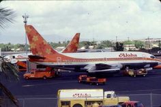 an orange and white airplane is parked on the tarmac at an airport with other vehicles around it