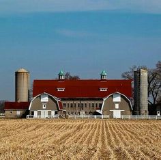 a farm with two silos and a barn in the background