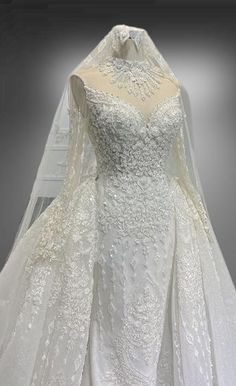 a white wedding gown on display in front of a gray background with an image of the bride's dress