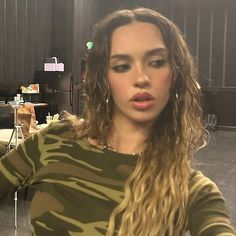 a woman with long curly hair is posing for the camera in a room full of tables and chairs