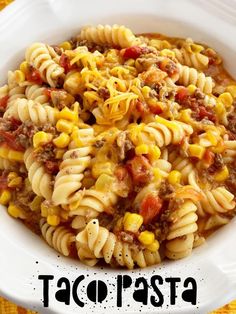 a white bowl filled with taco pasta on top of a yellow table cloth and the words taco pasta above it