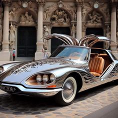 a silver car parked in front of a building with ornate carvings on it's side