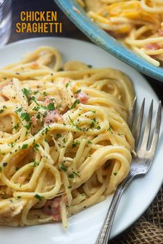 a plate of pasta with ham and parsley on it next to a glass of water