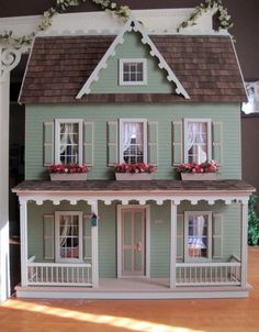 a doll house is shown with flowers in the windows