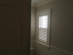 an empty room with white walls and shutters