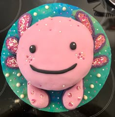 a pink cake with sprinkles and a smiling face