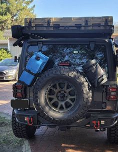 the back end of a black jeep parked in front of a house