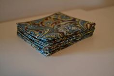 a stack of four blue and brown paisley patterned napkins on a white counter top