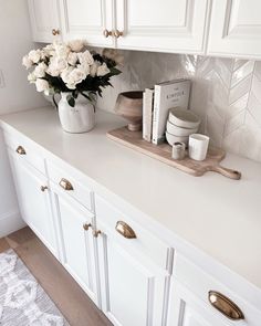 a kitchen counter with white cabinets and flowers