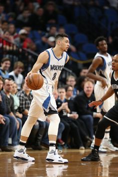 two basketball players are on the court with people watching them and one is holding a ball