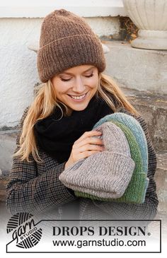 a woman sitting on the steps with her hat and scarf wrapped around her neck, smiling