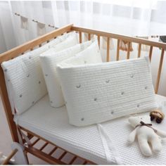 a baby crib with three pillows and a stuffed animal