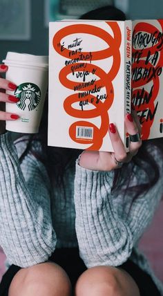 a woman holding up a starbucks book with her hands