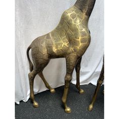 a gold giraffe statue is standing in front of a white curtain and black floor