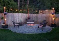 an outdoor fire pit surrounded by chairs and lights