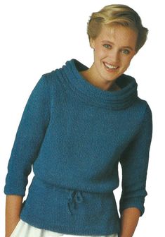 a woman wearing a blue sweater with a cowl neck and bow at the waist