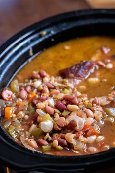 a close up of a bowl of soup with beans and meat in it on a table