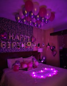 a bed with purple lights and balloons on the headboard in a bedroom decorated for a birthday party